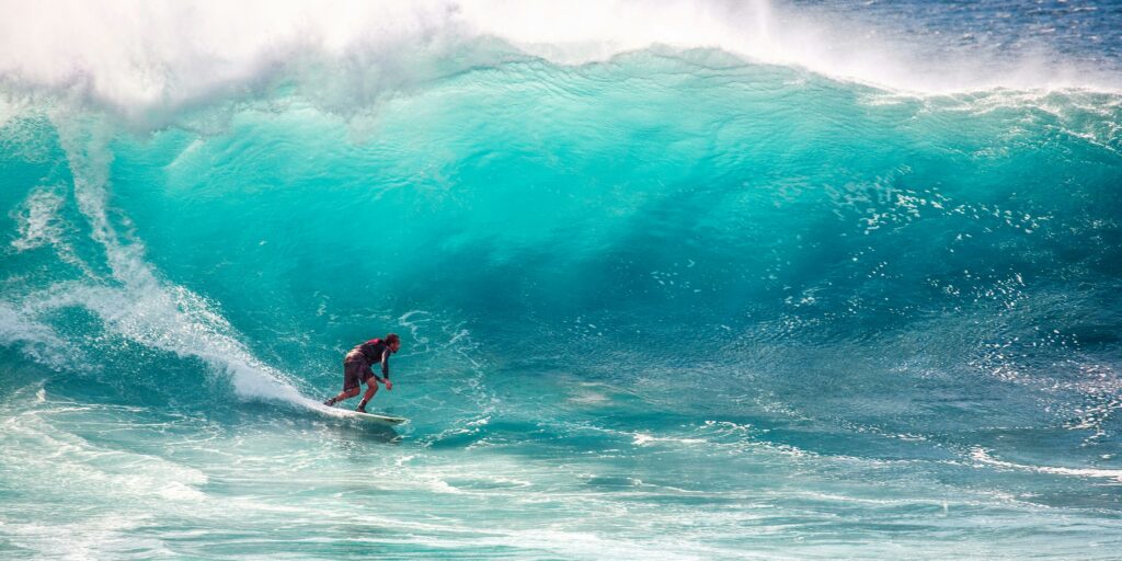 Thrilling surfing on massive turquoise waves, capturing the essence of ocean sports and adventure.
